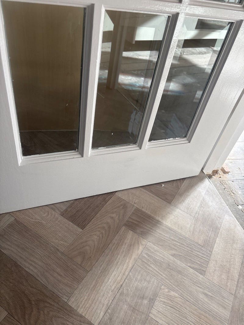 Glazed internal door freshly painted, above a herringbone floor