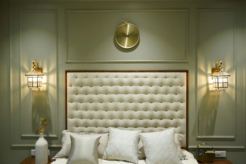 Bedroom with olive panelled walls and brass wall lights