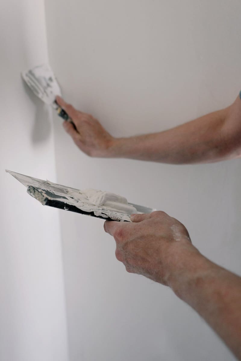Hands filling a wall with a filling knife and hawk