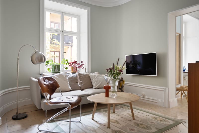 Light sage living room with tall windows and panelled walls