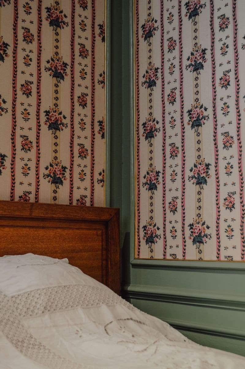 Bedroom with striped floral wallpaper above green panelling